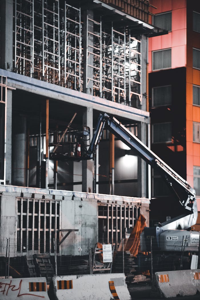 A detailed view of an urban construction site with heavy machinery at night.